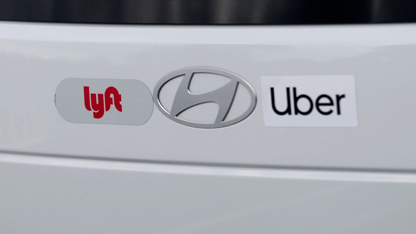 Logos for Lyft, Uber, and Hyundai on a white car's rear panel.