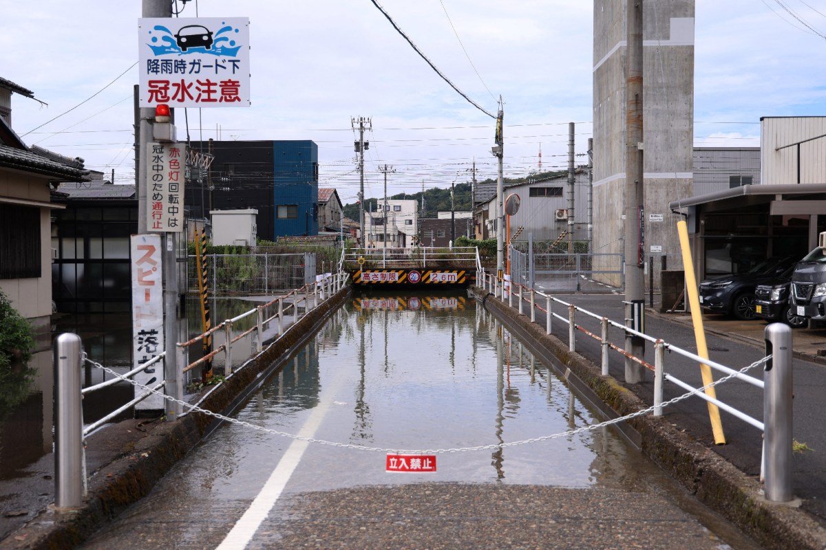 A flooded area on a street with warning signs and a barricade.