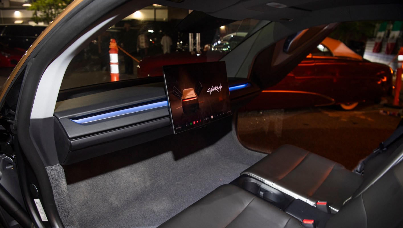 An interior view of a car with a mounted screen displaying a Cybertruck image.