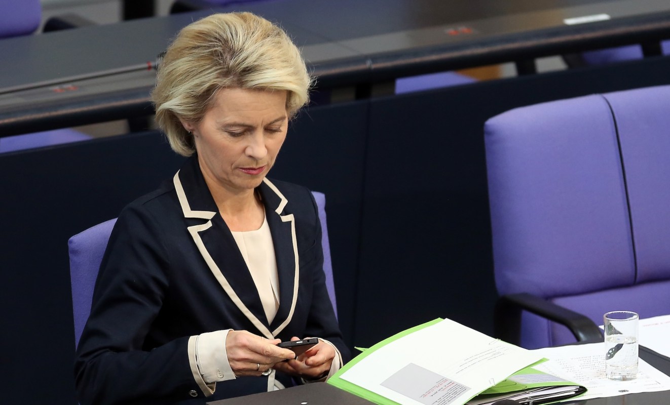 Ursula von der Leyen, president of the European Commission, seated at a table, focused on her smartphone.
