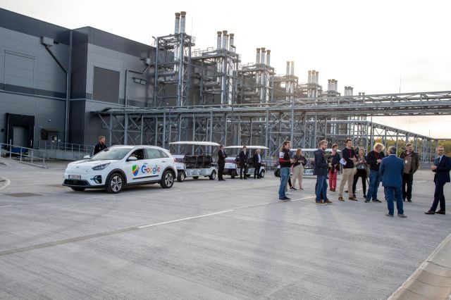 An SUV with a Google logo sits outside a data center as people explore the facility