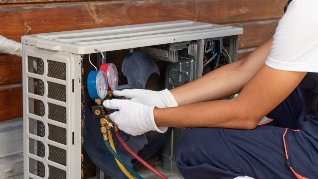 A technician works on an air conditioning unit.