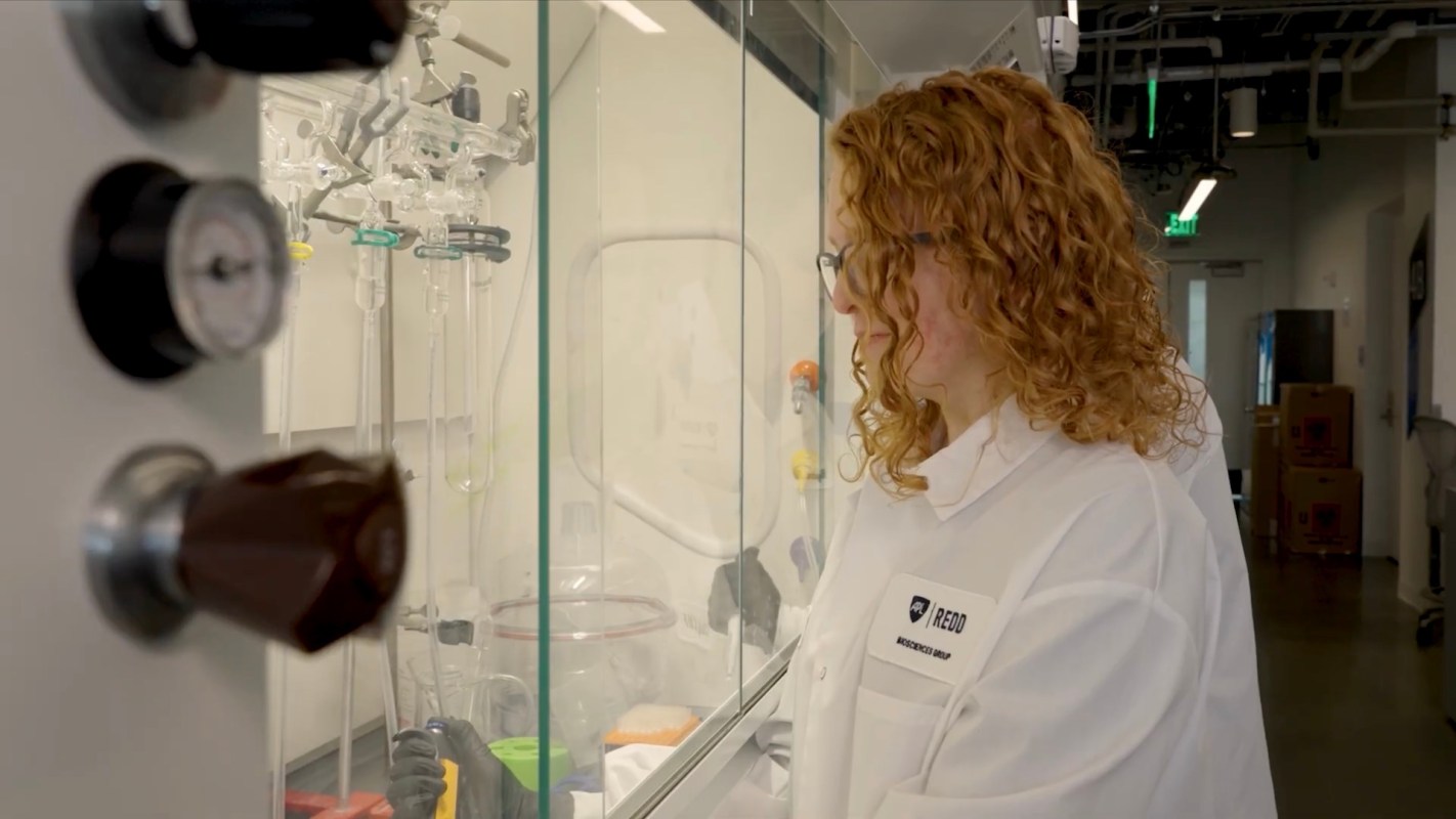 A person in a lab coat works near scientific equipment in a laboratory.
