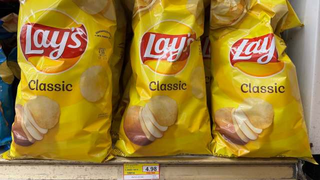 Three bags of Lay's Classic potato chips displayed on a shelf with a price tag of $4.98.