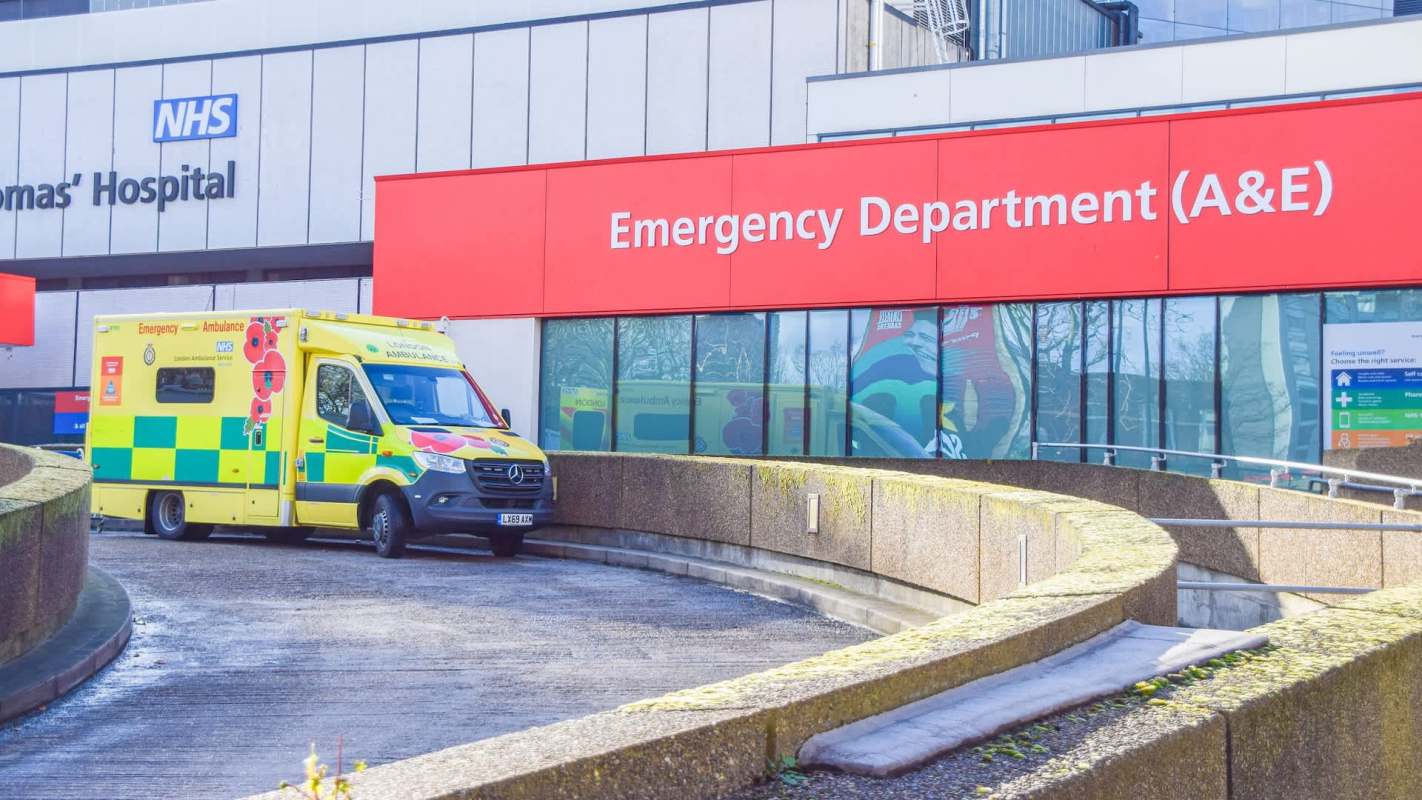 An ambulance parked outside the emergency department of a hospital building.