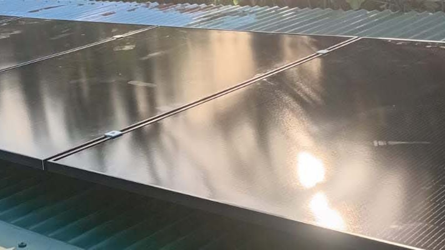 Solar panels installed on a roof with sunlight reflecting off their surface.