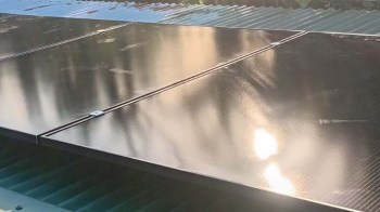 Solar panels installed on a roof with sunlight reflecting off their surface.