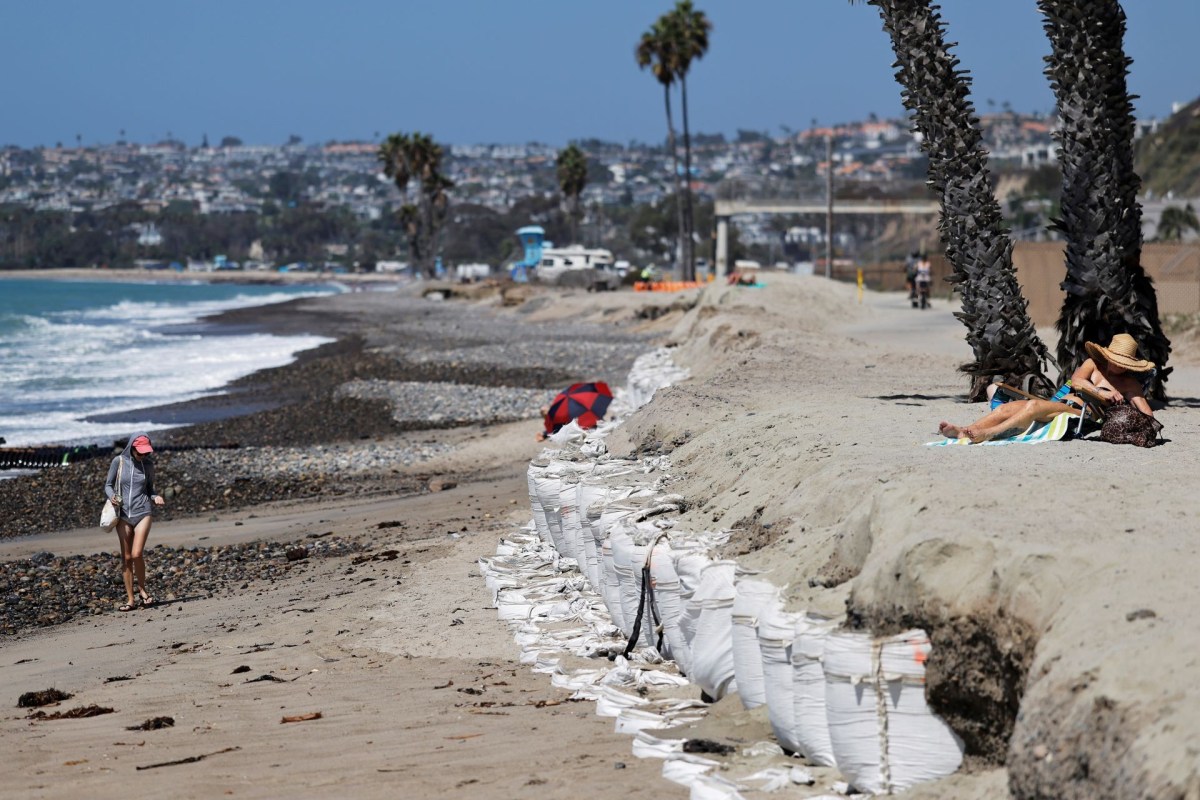 A beach in Orange County California has a wall of eroding sand as beachgoers use the beach