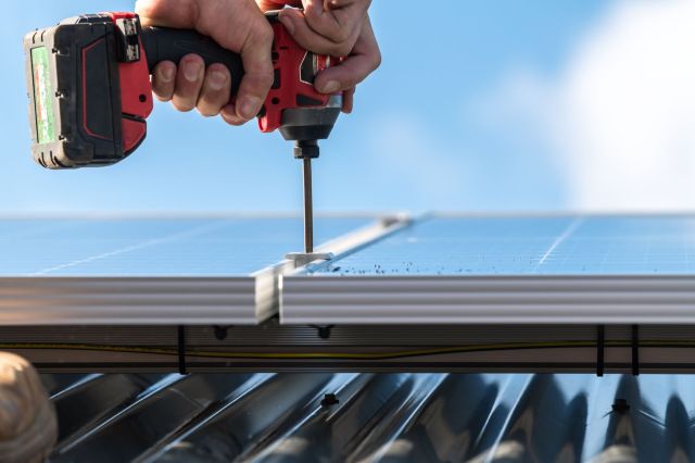 A person drilling into a solar panel.