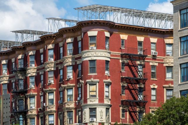 A red brick apartment building in New York has solar panels on the roof