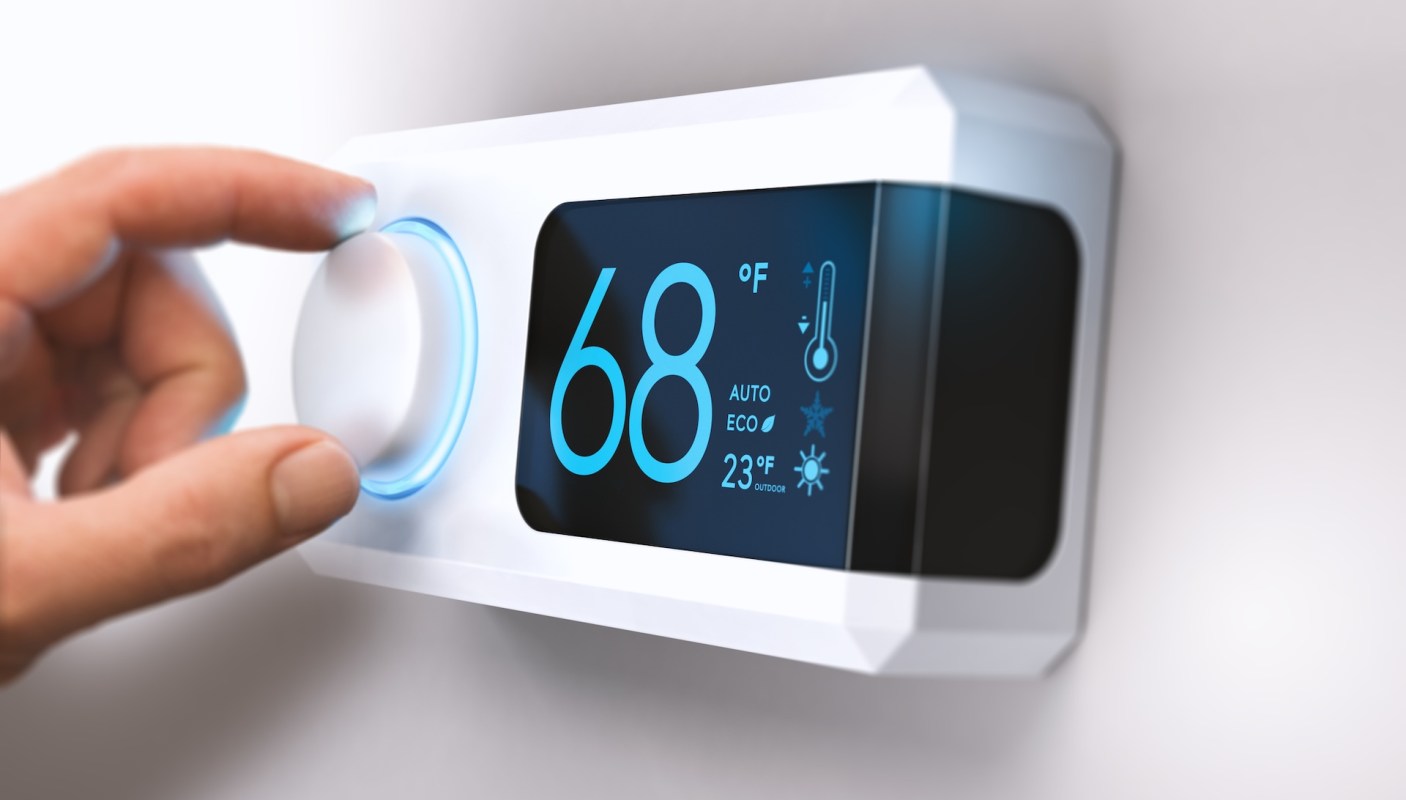 A hand adjusts a modern thermostat displaying a temperature of 68°F.