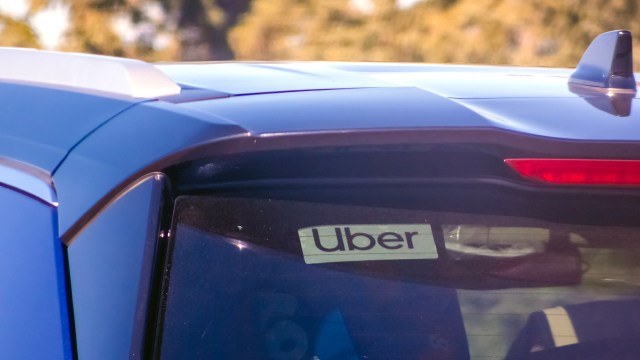 A blue car with an Uber sticker on the rear window.