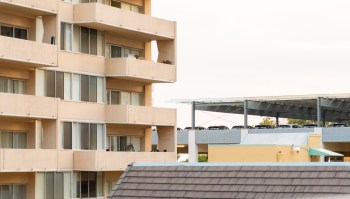 A multi-story building with balconies next to a parking structure.