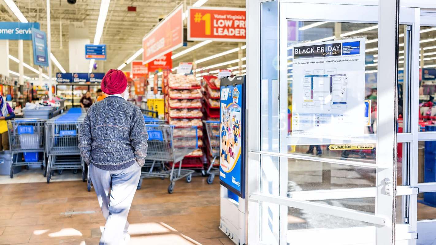 A person walks into a Walmart displaying a Black Friday store map and shopping carts in the background.