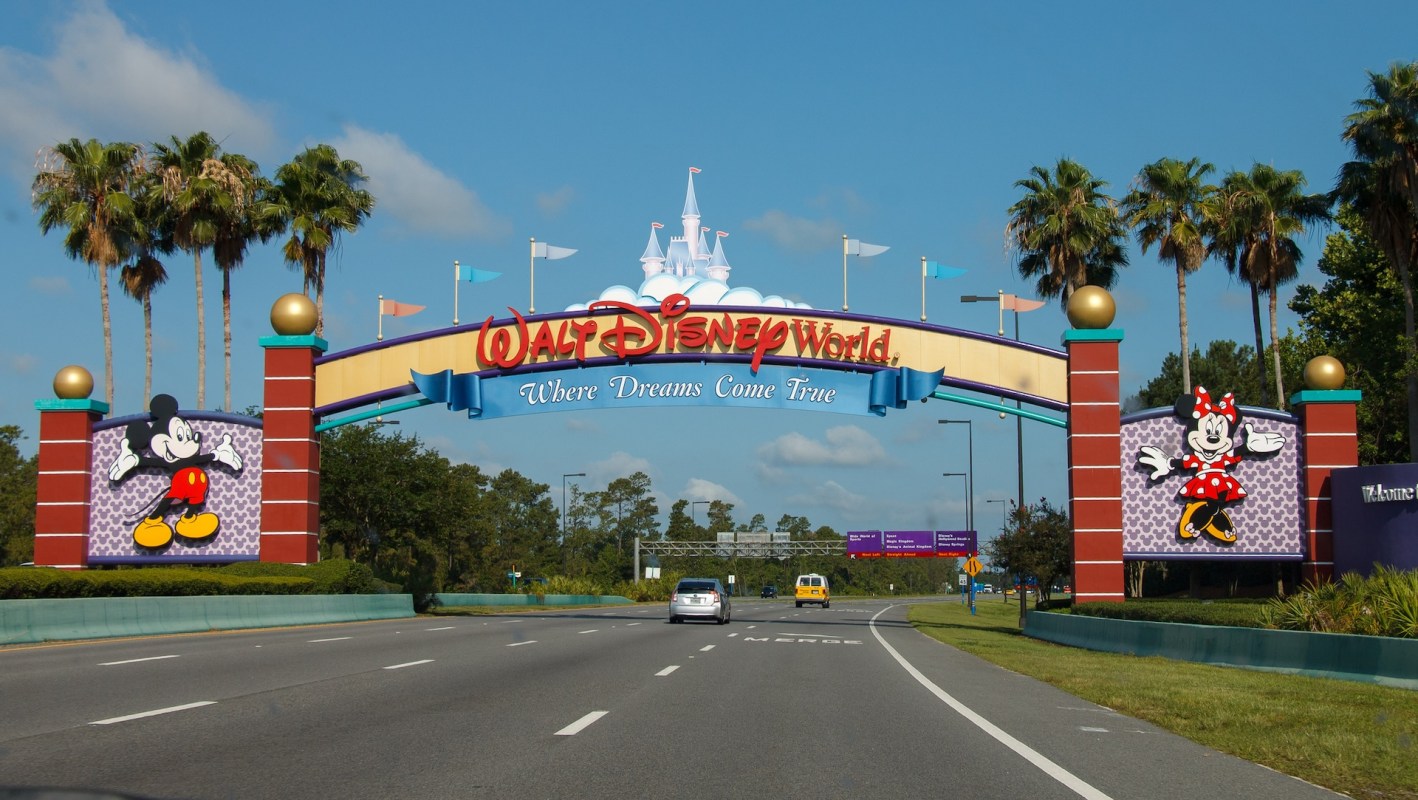 Walt Disney World entrance sign featuring Mickey and Minnie Mouse with palm trees in the background.
