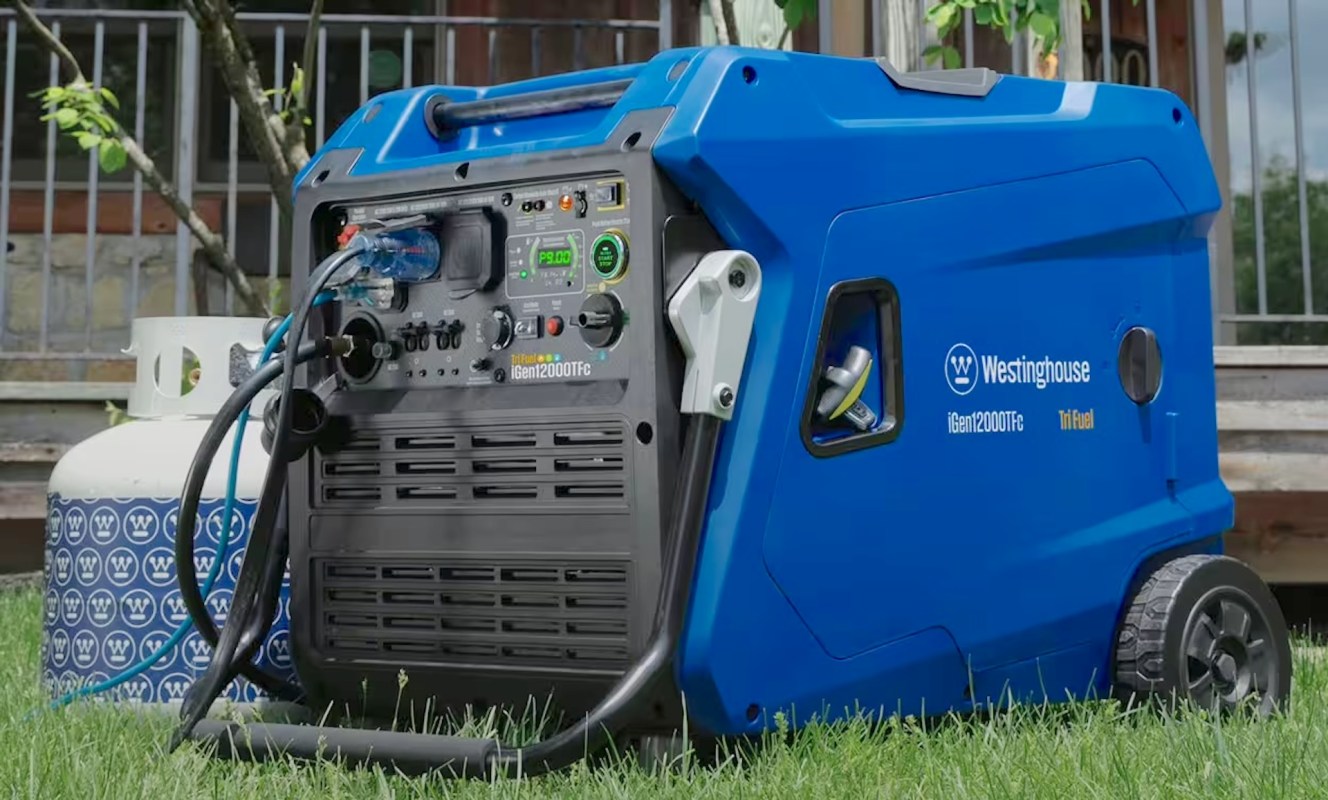 A blue generator with various ports and a propane tank nearby, sitting on grass.
