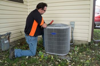 A technician working on an outdoor AC unit.