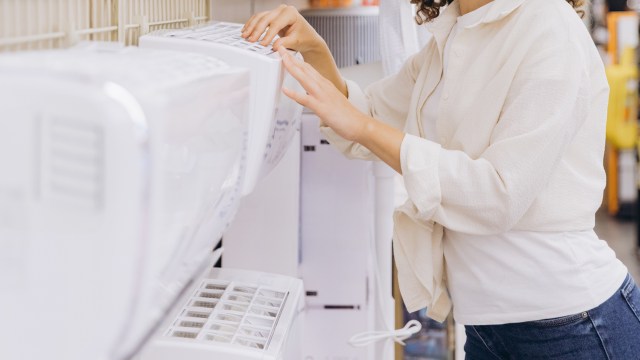 A person adjusts the settings on a display appliance in a store.