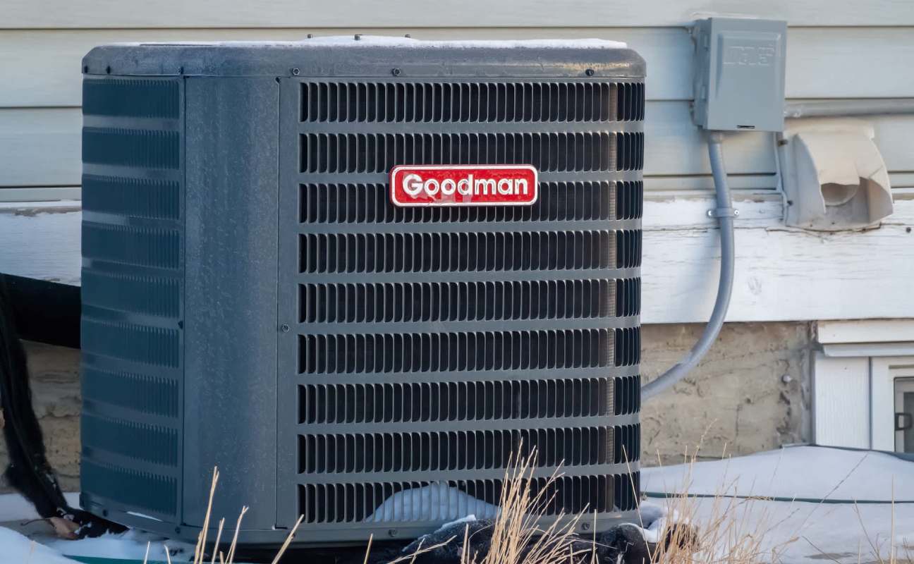 An outdoor air conditioning unit with a red and white Goodman logo.