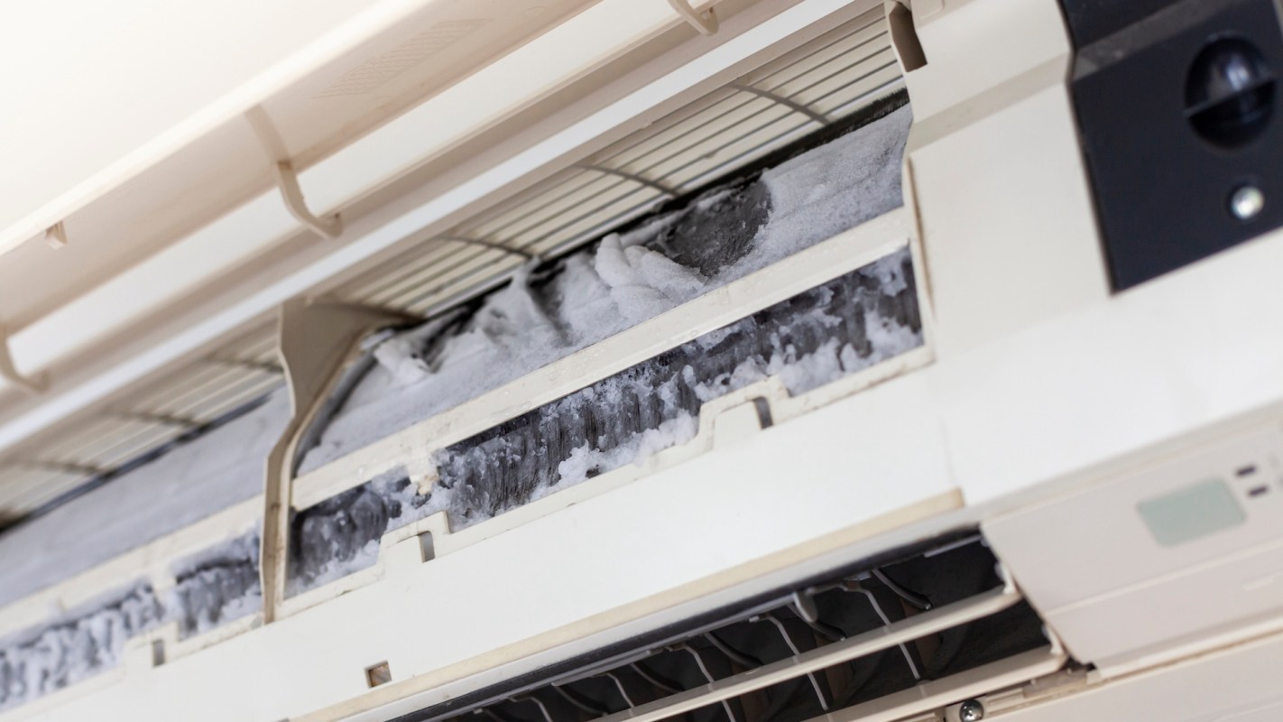 An air conditioning unit with ice buildup inside the filter compartment.