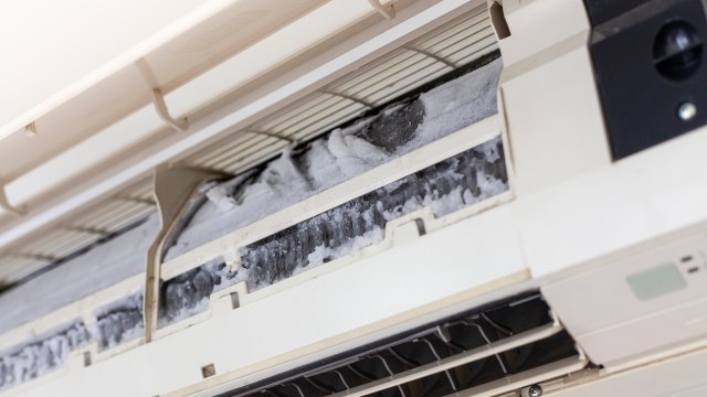 An air conditioning unit with ice buildup inside the filter compartment.