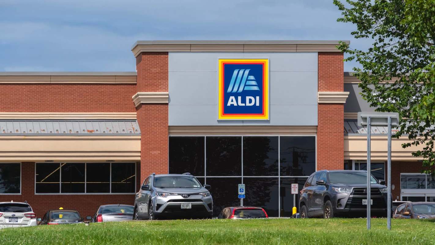 A grocery store building with an Aldi sign and parked cars in front.