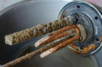 A corroded heating element with buildup and rust in a metal container.