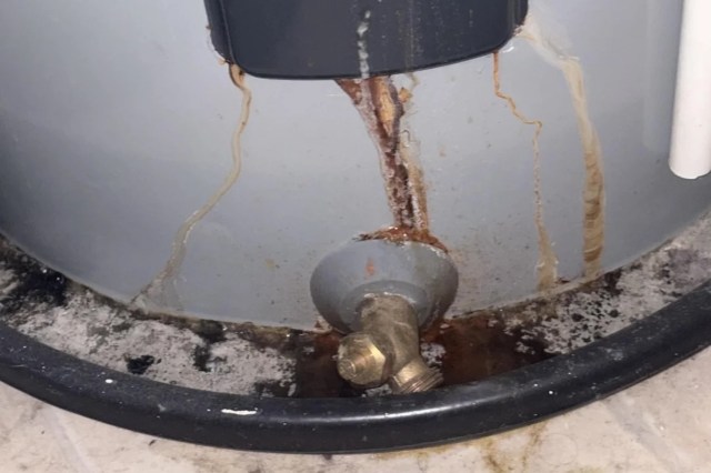 A water heater with visible rust and leaking water near the base.