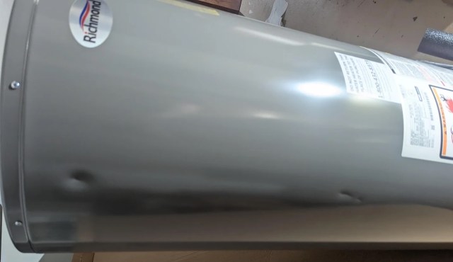 A silver water heater with a label and visible indentations.