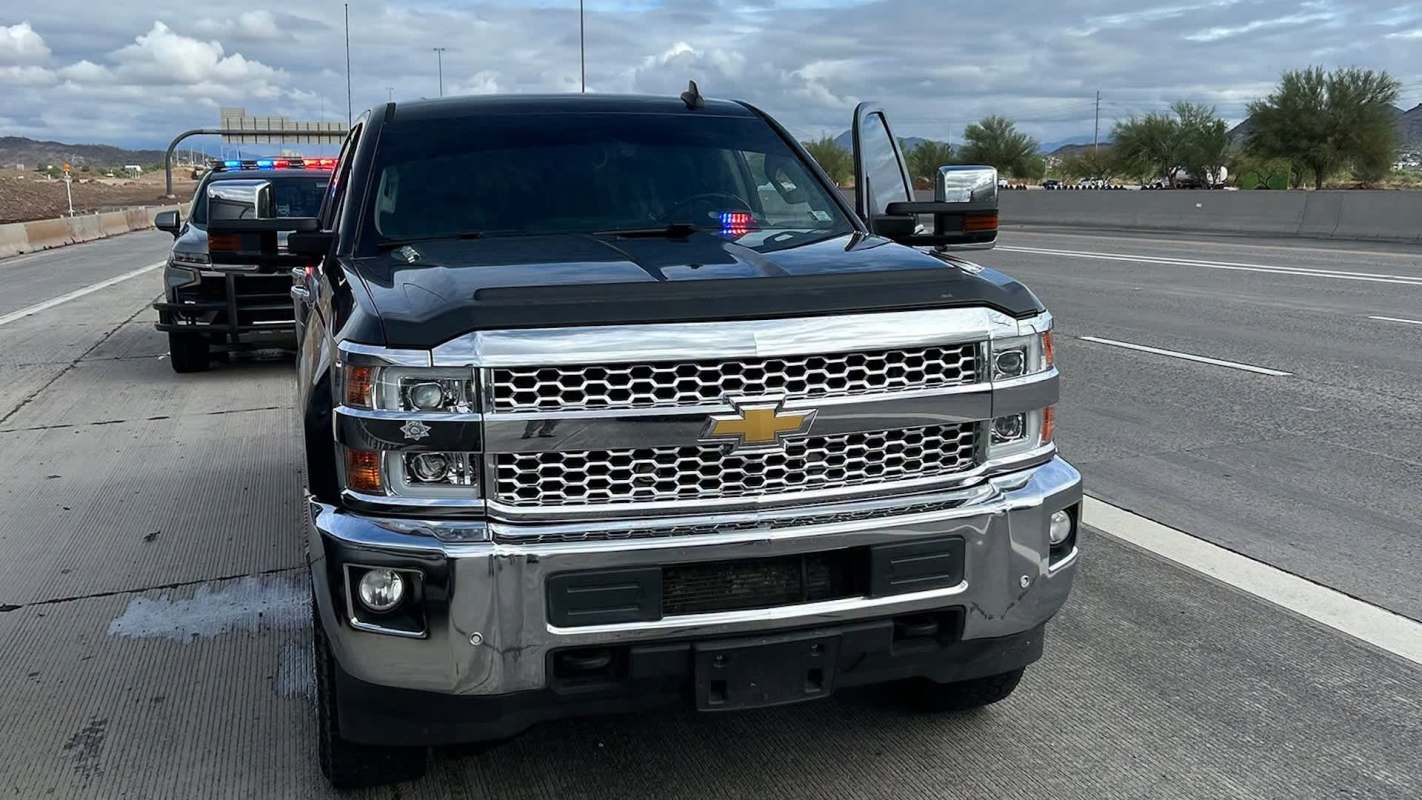 A black Chevrolet truck with police lights parked on a highway.
