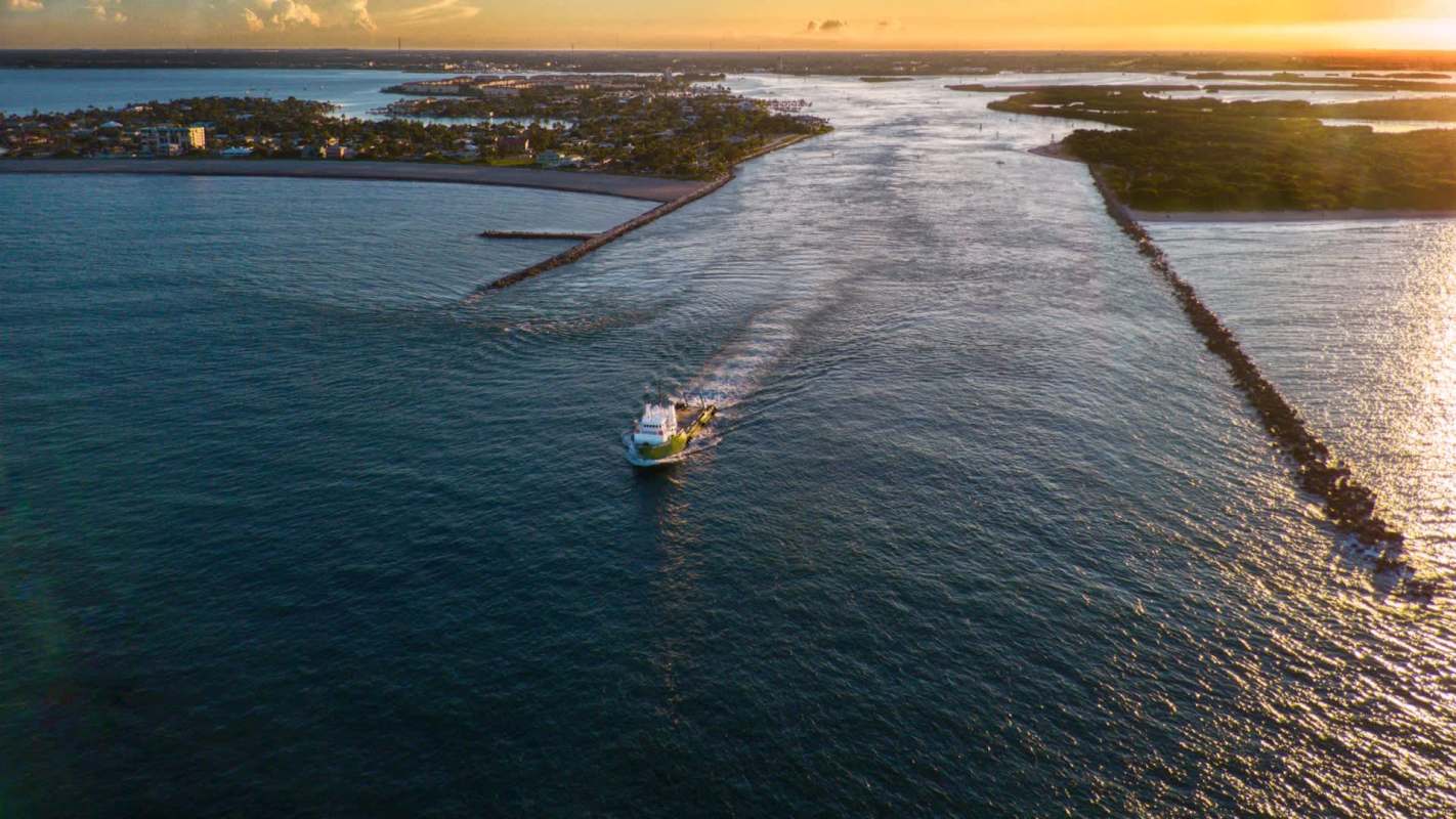 A boat navigating through an inlet at sunset.