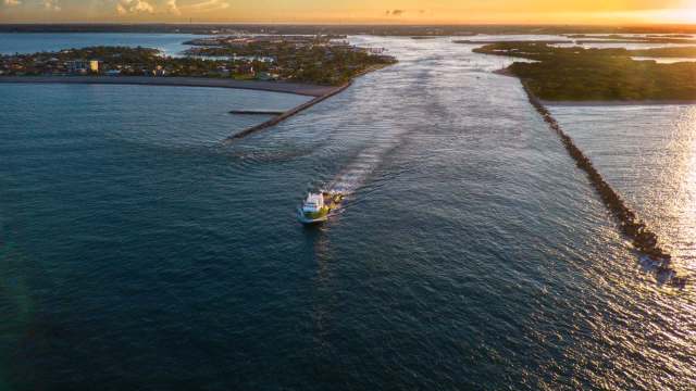 A boat navigating through an inlet at sunset.