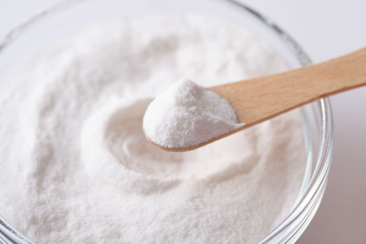 A spoon has a scoop of artificial sweetener over a bowl