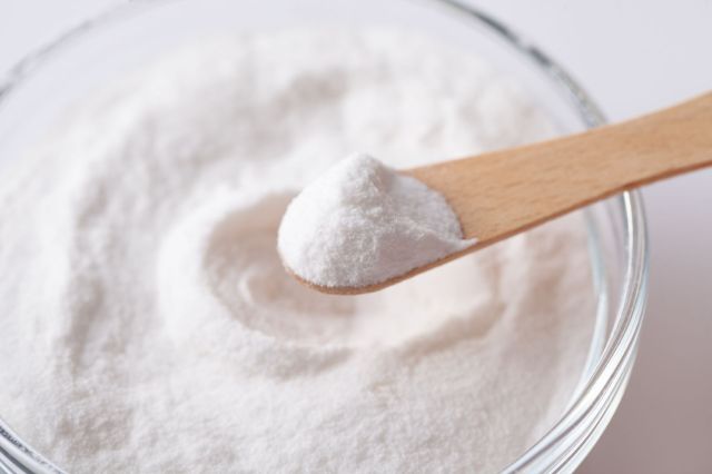 A spoon with a scoop of artificial sweetener over a bowl.