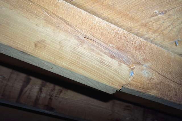 A wooden beam showing visible grain and a crack along the surface.