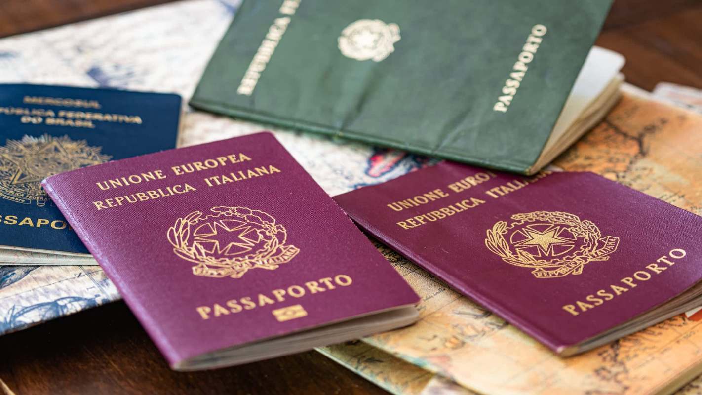 A collection of passports arranged on a wooden surface, with some maps visible underneath.