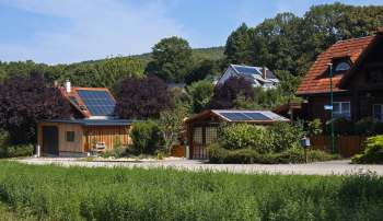 A cluster of houses with solar panels surrounded by greenery and trees.