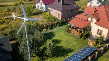 A residential area with a wind turbine and solar panels.