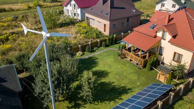 Houses near a wind turbine and solar panels.