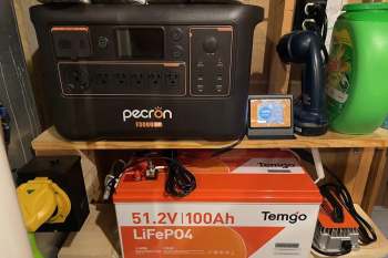 A power station and a battery displayed on a shelf alongside various household items.
