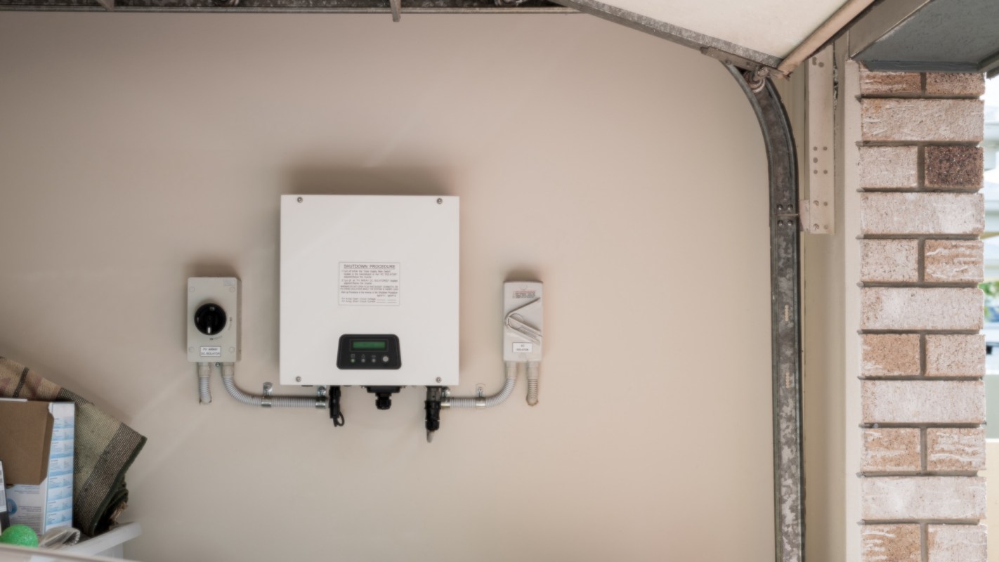 A wall-mounted electrical box with a control panel and connected wiring in a garage.