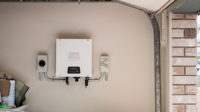A wall-mounted electrical box with a control panel and connected wiring in a garage.