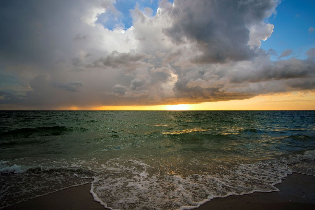 A thunderstorm with clouds in the distance from the shore of a beach