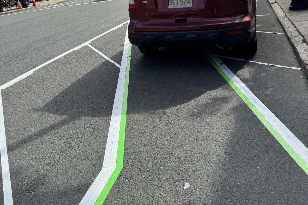 White and green markings on an asphalt street with an SUV parked nearby