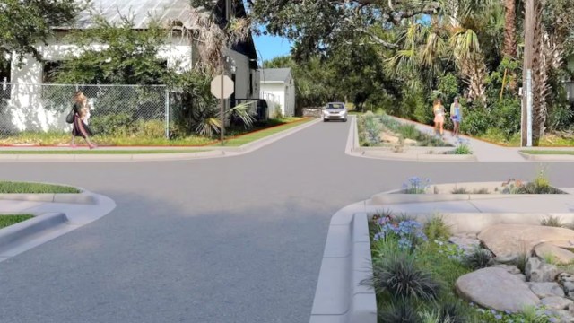 A street scene featuring pedestrians walking, landscaped areas, and a car approaching an intersection.