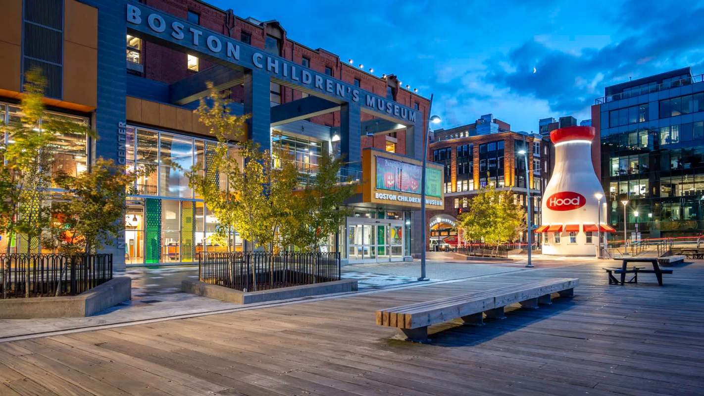 The Boston Children's Museum exterior with a large milk carton sculpture nearby, surrounded by trees and walkways.