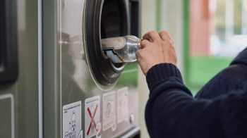 A person inserts a plastic bottle into a recycling machine.