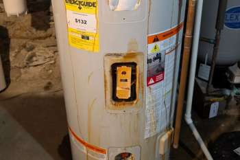 A water heater with rust and stains, displaying warning labels and an EnergyGuide sticker.