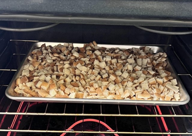 Cubed bread on a baking tray inside an oven.