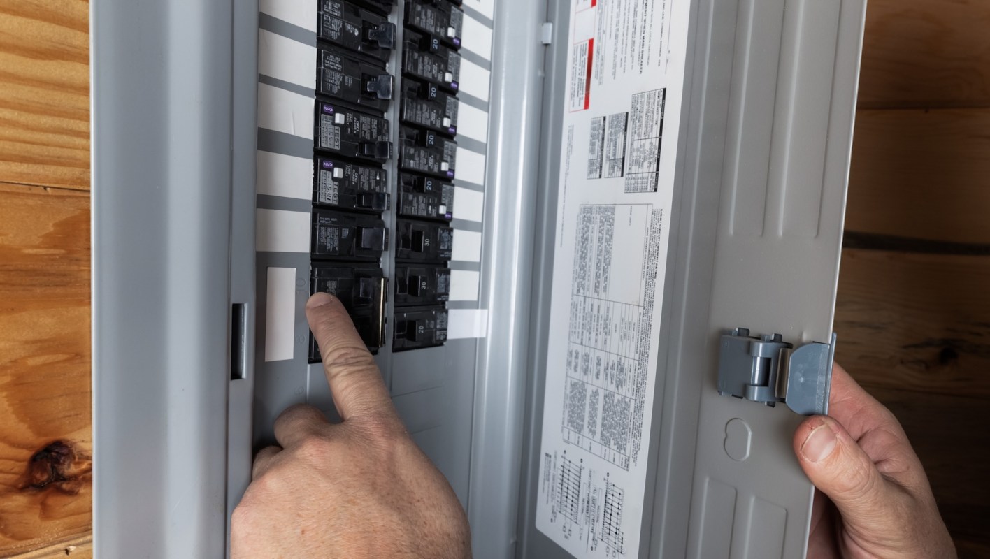 A person interacts with a circuit breaker panel.